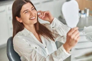 A successful dental treatment showing a perfect, fully restored smile in a hand mirror.